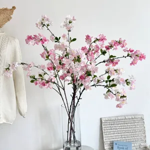 Elegante kunstmatige roze appelbloesemtakken in een glazen vaas voor huisdecoratie