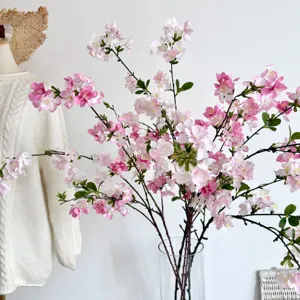 Detail van kunstmatige kersenbloesems met roze en witte bloemblaadjes in een vaas.