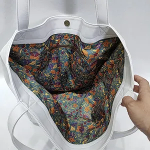 Primer plano del forro floral y el bolsillo con cremallera de la bolsa blanca