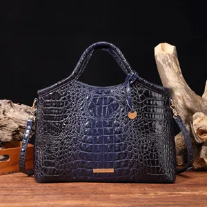 Vista detallada del bolso azul marino con grabado de cocodrilo sobre fondo madera