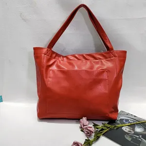 Vista detallada del bolso tote de cuero rojo encerado con un práctico bolsillo frontal