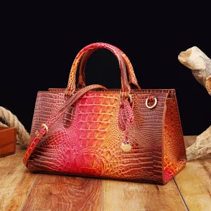 Bolso vintage con relieve de cocodrilo degradado rojo y marrón sobre mesa de madera