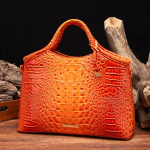 Vista detallada del bolso naranja brillante con relieve de cocodrilo sobre fondo de madera