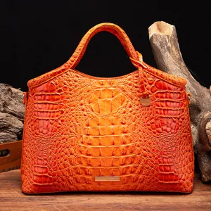 Vista detallada de bolso naranja con grabado de cocodrilo sobre fondo de madera rústica