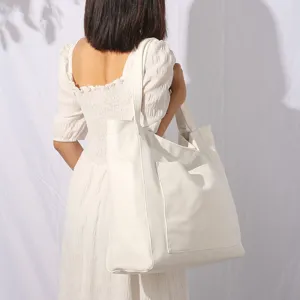 Detalle profesional de un bolso tote grande de cuero suave blanco con bolsillo