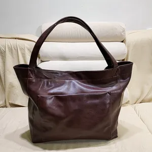 Vista frontal de un bolso tote vintage marrón con un gran bolsillo exterior frontal