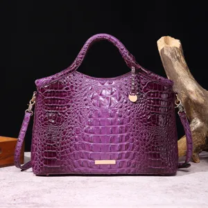Primer plano de bolso vintage morado con textura de cocodrilo en relieve y metal dorado.