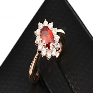 Close-up of elegant rose gold ring featuring a vibrant red oval zircon in a halo setting.