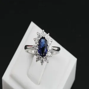 Detailed view of silver-tone halo ring with a large blue oval stone and clear crystals