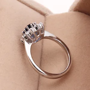 Close-up side view of an elegant oval blue stone halo ring in a tan velvet jewelry box