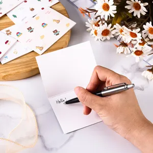 Detailed view of a hand writing 'Hello' on a cute mini cartoon animal greeting card