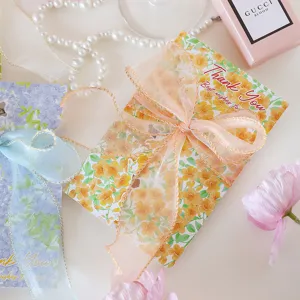 Close-up of floral thank you card decorated with elegant sheer ribbon and gold edges.