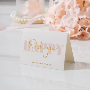 Primer plano de una elegante minitarjeta de felicitación con letras doradas y texto HAPPY rosa