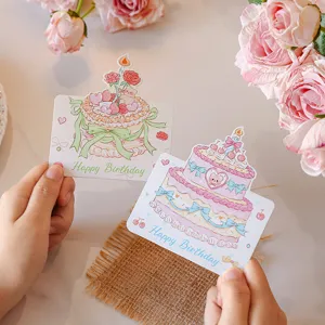 Detailed view of two cute cake-themed birthday cards with Happy Birthday text held in hands.