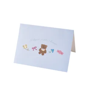Cute pastel blue greeting card featuring a cartoon bear and colorful illustrations.