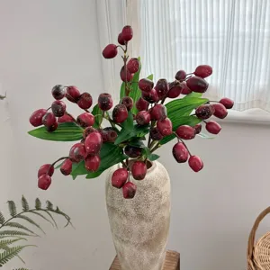 Realistic artificial red zombie fruit branch with leaves in a textured ceramic vase