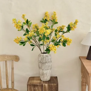 Detailed view of artificial yellow lilac flowers in a textured vase for home decor