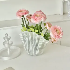 Realistic pink artificial Persian buttercup flowers in a wavy frosted glass vase for decor
