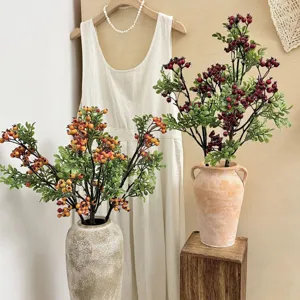 Artificial red and yellow berry stems in rustic ceramic vases for home interior decor.