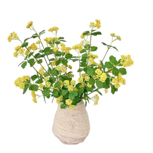 Prachtige gele kunstmatige rijstvruchtbloemen in een beige getextureerde vaas
