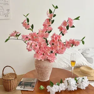 Artificial pink cherry blossom branches in a ceramic vase for elegant home living room decor