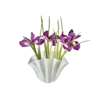 Artificial purple iris flowers in elegant white ribbed glass vase on white background