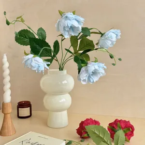 Close-up of elegant light blue artificial peony flowers in a stylish minimalist white vase