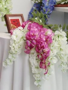Nahaufnahme von realistischen rosa und weißen hängenden Blauregenblüten auf dem Tisch.