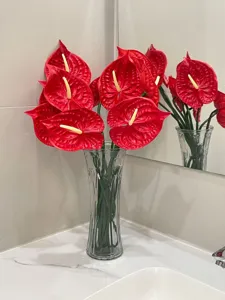 Vivid red artificial anthurium flowers displayed in a clear glass vase for home decor