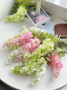 Elegante künstliche Blauregenblüten in Rosa und Weiß auf einer minimalistischen Tischszene