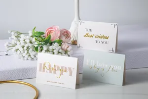 Vista detallada de elegantes tarjetas de felicitación con letras doradas y flores.