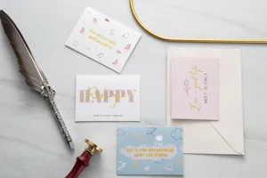 Primer plano de tarjetas de felicitación doradas con pluma estilográfica y sello de cera.