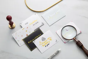 Detalle de varias tarjetas de felicitación con pan de oro y mensajes elegantes de deseo