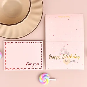 Vista dall'alto di eleganti biglietti d'auguri in lamina d'oro rosa con design Birthday