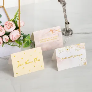 Vista macro de tres elegantes tarjetas de felicitación doradas con flores y corazones