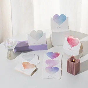 Close-up of watercolor heart greeting cards with Best Wishes text on a styled table