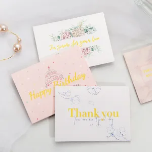 Detalle de tarjetas de felicitación florales doradas con mensajes de cumpleaños y gracias.