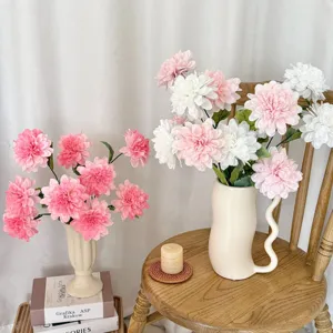 Beautiful pink and white artificial dahlias in stylish ceramic vases on a chair.