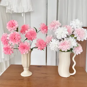 Macro view of pink and white artificial dahlia flowers in elegant cream ceramic vases