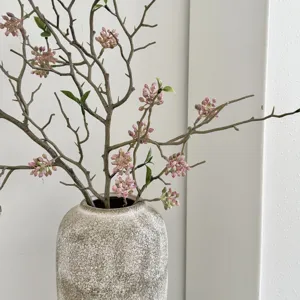 Λεπτομέρεια τεχνητού κλαδιού Wabi-sabi με ροζ μούρα σε ρουστίκ κεραμικό βάζο