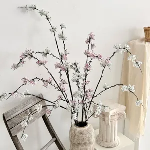 Kunstmatige sneeuwwilg takken met roze en witte bloemen in een rustieke vaas voor huisdecor