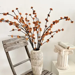 Ramas de bayas naranjas artificiales en un jarrón para decoración de hogar minimalista