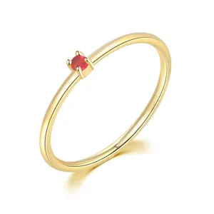 Elegante anillo fino de oro minimalista con una pequeña piedra de circonita roja
