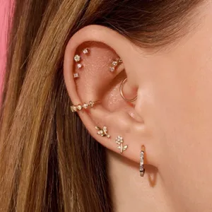 Close-up showing a stylish collection of gold flower and CZ cartilage stud earrings on an ear