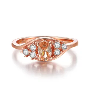 Primer plano detallado de anillo de oro rosa con piedra ovalada amarilla y cristales finos.