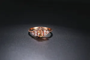 Primer plano del anillo bañado en oro rosa con piedra amarilla ovalada y detalles.