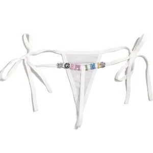 Primer plano de tanga blanco transparente con abalorios de letras de estrás y lazos laterales.