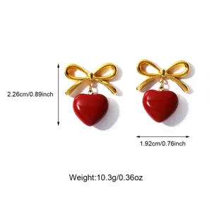 Close-up detail showing dimensions and weight of gold bow with red heart drop earrings