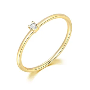 Primer plano de un anillo minimalista bañado en oro con una pequeña piedra de circón.