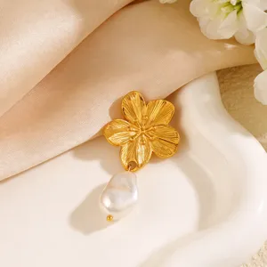 Primo piano di un'elegante spilla a fiore dorato con ciondolo in perla barocca bianca naturale
